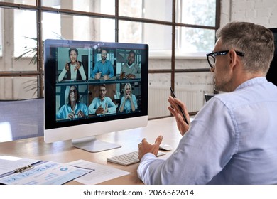 Corporate Leader Manager Leading Videoconference With Diverse Team Business People Having Digital Group Video Call Conference Working In Office At Online Virtual Meeting On Pc Computer. Over Shoulder