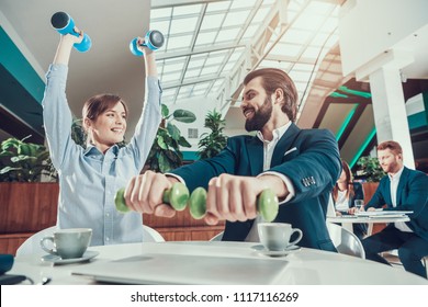 Corporate Lifestyle Healthcare Concept Of Business People In Office Interior Working With Dumbbells. Workers Doing Fitness Exercises Of Yoga Practice. Wellbeing Employee Man Smiling To Healthy Woman