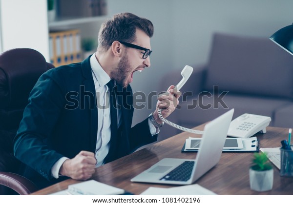 Corporate mad people yell authority tell speak with\
staff people person concept. Side profile view portrait of\
disappointed tired busy sad upset agent financier shouting on\
receiver in his hand