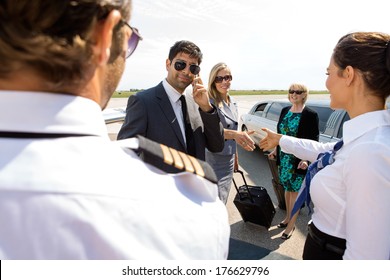 Corporate Man And Women Greeting Pilot And Airhostess At Airport Terminal