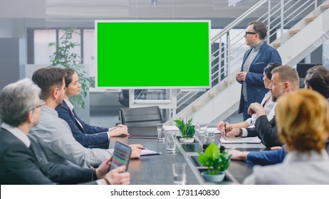 In the Corporate Meeting Room: Creative Director Uses Digital Chroma Key Interactive Whiteboard for Presentation to a Board of Executives, Lawyers, Investors. Green Mock-up Screen in Horizontal Mode - Powered by Shutterstock