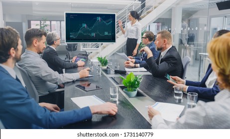 In The Corporate Meeting Room: Female Analyst Uses Digital Interactive Whiteboard For Presentation To A Board Of Executives, Lawyers, Investors. Screen Shows Company Growth Data With Graphs