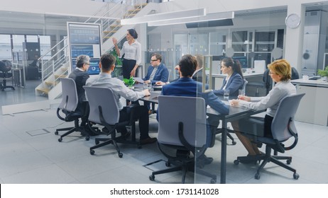 In The Corporate Meeting Room: Female Analyst Uses Digital Interactive Whiteboard For Presentation To A Board Of Executives, Lawyers, Investors. Screen Shows Company Growth Data With Graphs