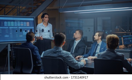 In The Corporate Meeting Room: Female Executive Talks And Uses Digital Interactive Whiteboard For Presentation To A Board Of Directors, Investors. Screen Shows Growth Data. Late At Night Office