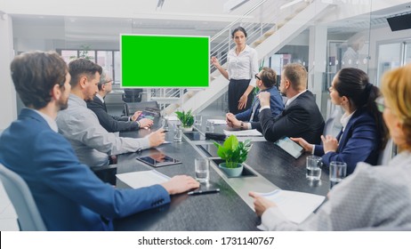 In the Corporate Meeting Room: Female Speaker Uses Digital Chroma Key Interactive Whiteboard for Presentation to a Board of Executives, Lawyers, Investors. Green Mock-up Screen in Horizontal Mode - Powered by Shutterstock