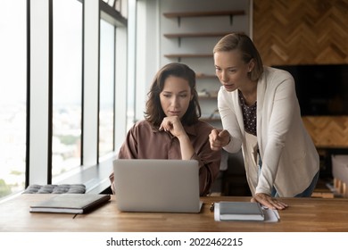 Corporate mentor supervising work of intern, giving help and professional advice, training skills of new employee. Managers meeting at laptop, discussing content on screen, talking. Teamwork concept - Shutterstock ID 2022462215