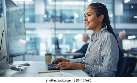 Corporate Office: Black Female IT Technician Using Desktop Computer, Uses Big Data Statistics, Graphs. Smiling Creative Software Engineer Work On ECommerce Project Marketing, Development.