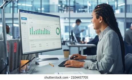 Corporate Office: Black Female IT Technician Using Desktop Computer with Big Data Statistics, Graphs. Smiling Creative Software Engineer Work on eCommerce Project Marketing, Development. - Powered by Shutterstock