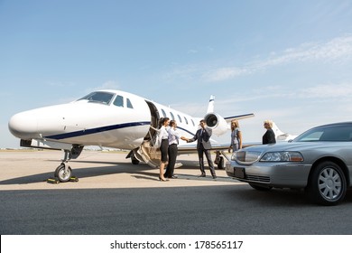 Corporate people greeting airhostess and pilot near private jet and limo at airport terminal - Powered by Shutterstock