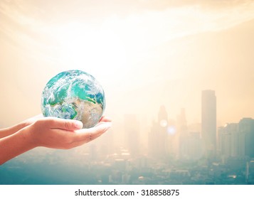 Corporate social responsibility (CSR) concept: Human hands holding earth 	
global over blurred big city background. Elements of this image furnished by NASA