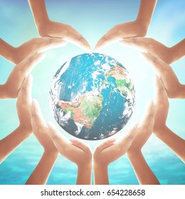 Corporate Social Responsibility (CSR) Concept: Heart Shape Of Hands Holding Earth Globe Over Blurred Blue Sea And Sky Background. Elements Of This Image Furnished By NASA