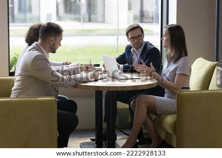 Corporate staff, company management solve business in office, share solutions, search decisions talking sit at table with laptop, female team leader makes speech at negotiations meeting with partners