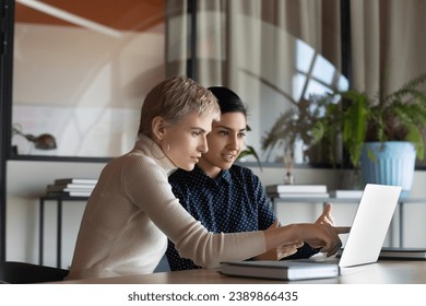 Corporate teacher showing new employee learning video at laptop, company mentor training intern. Diverse coworkers watching presentation, reading message, working together at computer - Powered by Shutterstock