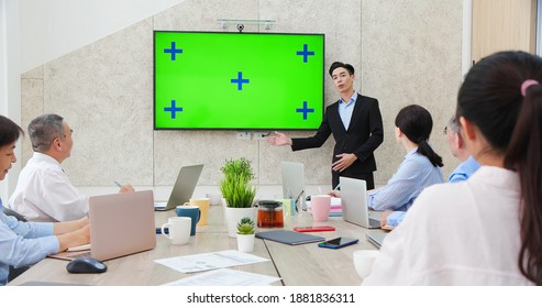 Corporate teamwork - Young Asian businessman lead group of business team in strategic meeting presentation with green screen TV - Powered by Shutterstock