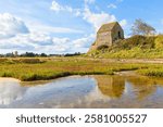 Corpse de Garde, medieval guard house at Saint-Germain-Sur-Ay, Cotentin peninsula, Normandy, France, reflected in a puddle.