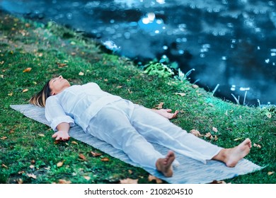 Corpse Position, Savasana, Meditation. Young Woman Practicing Yoga And Meditating By The Water.