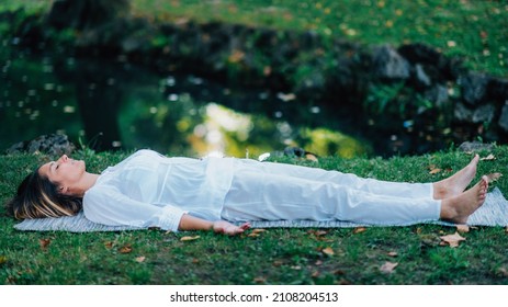 Corpse Position, Savasana, Meditation. Young Woman Practicing Yoga And Meditating By The Water.