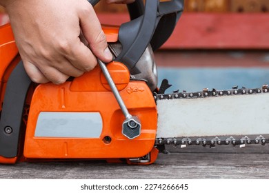 Correct chain tension using the special tool on the chainsaw bar. Chain tension adjustment. Close-up - Powered by Shutterstock