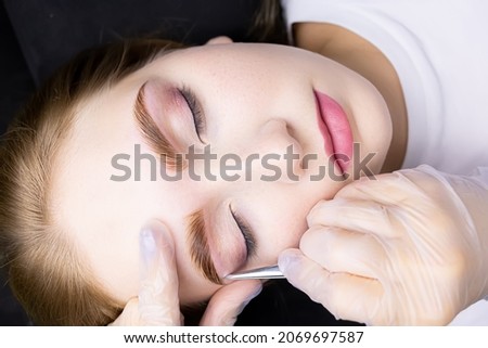 correction of the model's eyebrows with tweezers and removal of excess hairs from the contour of the eyebrows after the lamination and coloring procedure