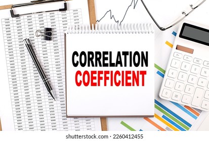 CORRELATION COEFFICIENT text on a notebook with chart, calculator and pen