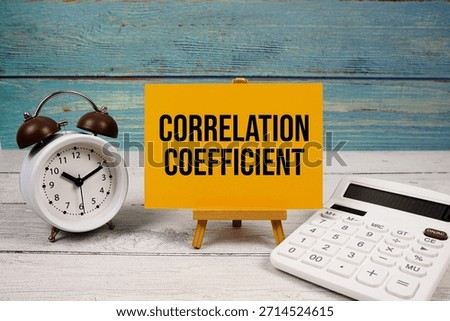 Correlation Coefficient text written on paper card with calculator and alarm clock on wooden background