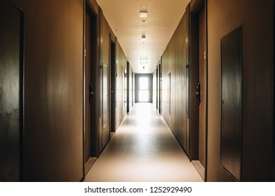 Corridor in the condomenium with light source at the end of the passage and green exit sign at the ceiling