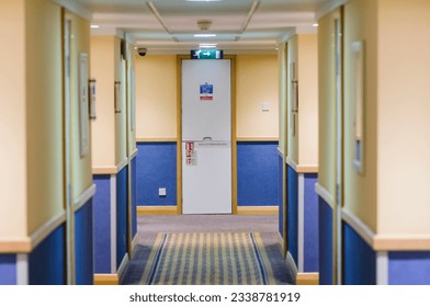 Corridor in a hotel looking down towards a fire escape.