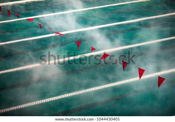 Corridor Lanes and flags in\
swimming pool with clean blue water. Fog over the water. Sport\
Competition.