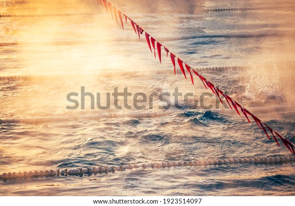 Corridor Lanes and flags in swimming pool\
with fog over the water. Sport\
Competition.