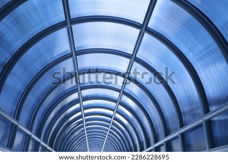 Corridor metal roof structure. Closeup of vaulted metal roof arches covered with blue polycarbonate sheets to block sunlight and rain for people walking between buildings in selective focus.