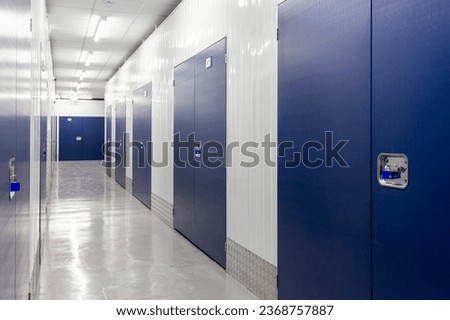 Corridor of self storage units with blue doors. Rental Storage Units