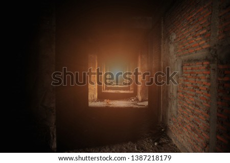Corridor within the building under construction Also see building structures and red brick walls Which has light from the end of the corridor Makes it look mysterious, but still see the exit far