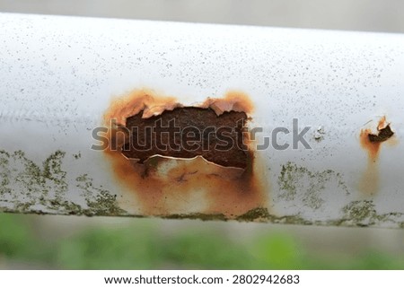 Corroded White Metal Pipe with Rust Hole and Peeling Paint