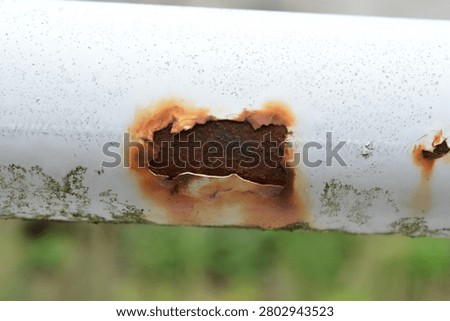 Corroded White Metal Pipe with Rust Hole and Peeling Paint. Corrosion, damage, aging infrastructure.