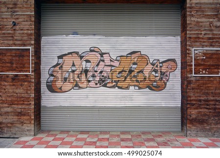 Corrugated metal sheet background, Street art of graffiti painted with spray paint on white painted Slide door on wooden walls, two empty frames on both sides. Urban contemporary culture.