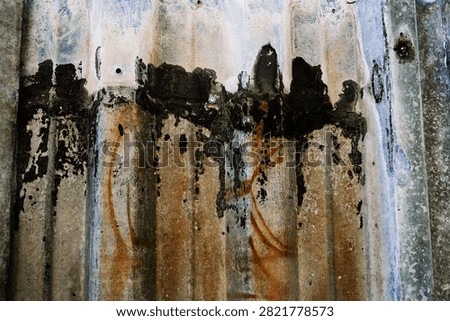 Corrugated metal surface with rust and peeling paint.