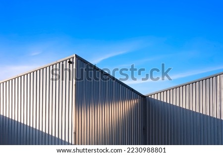 Corrugated Steel industrial Factory Building Wall against Blue Sky background with sunlight and shadow on surface