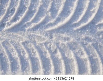 A corrugated track from a car that has already left, from symmetrically curved thin convex lines, in the sun, on white snow (macro, top view, horizontal, texture). - Powered by Shutterstock