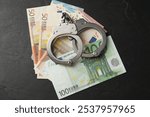 Corruption. Handcuffs and euro banknotes on grey textured table, flat lay