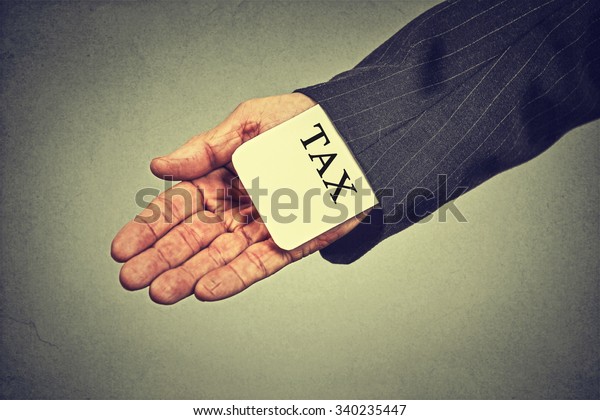 Corruption illegal criminal\
activity tax evasion economy ponzi scheme concept. Closeup man hand\
hiding tax card in a sleeve of a suit isolated on gray wall\
background 