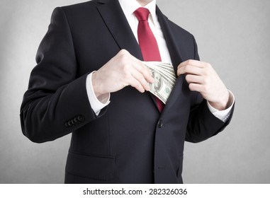 Corruption. Man Putting Money In Suit Jacket Pocket.