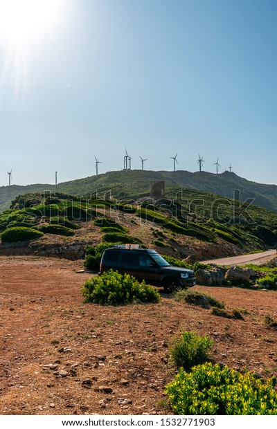 Corse, France - August 2019: Land Rover\
Discovery 4 black edition in off road near some wind energy fan in\
a beautiful sunny day. Vacation with\
car