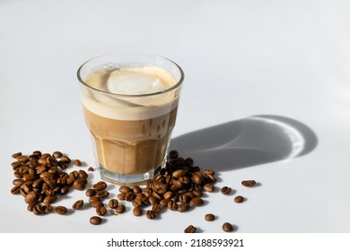 cortado coffee in a glass on a gray background with coffee beans with hard shadows - Powered by Shutterstock