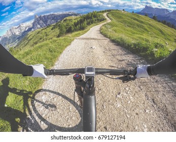 Corvara, Dolomites, Italy. Man Riding Mountain Bike On Single Trail On A Mountain Road. POV, Original Point Of View. Fish Eye Effects