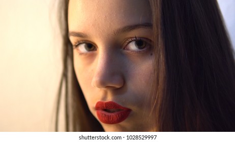 Cose up on model applying dark red lipstick