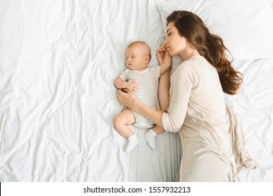 Co-sleeping With Infants. Millennial Mother Embracing Her Cute Little Baby During Sleep, Top View