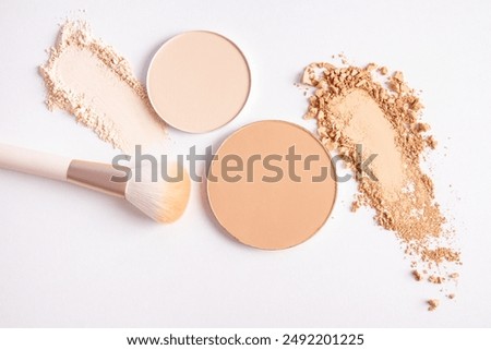 cosmetic background with texture samples of compact and loose powder in different tones. A chic makeup brush. top view. white background