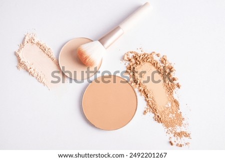 cosmetic background with texture samples of compact and loose powder in different tones. A chic makeup brush. top view. white background.