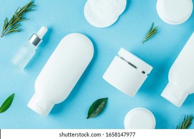 Cosmetic Background With White Tubes And Jars For Beauty Spa And Cosmetics Manufacturing. Flat Lay Blue Color.