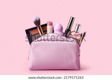 Cosmetic bag with different cosmetics and accessories on pink background